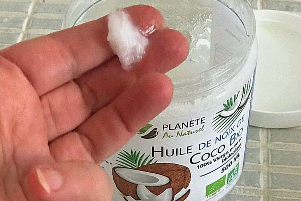 Une personne ayant une noisette d'huile de noix de coco sur ses doigts 
