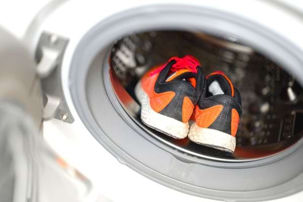 Une paire de basket orange posée à l'intérieur d'une machine à laver