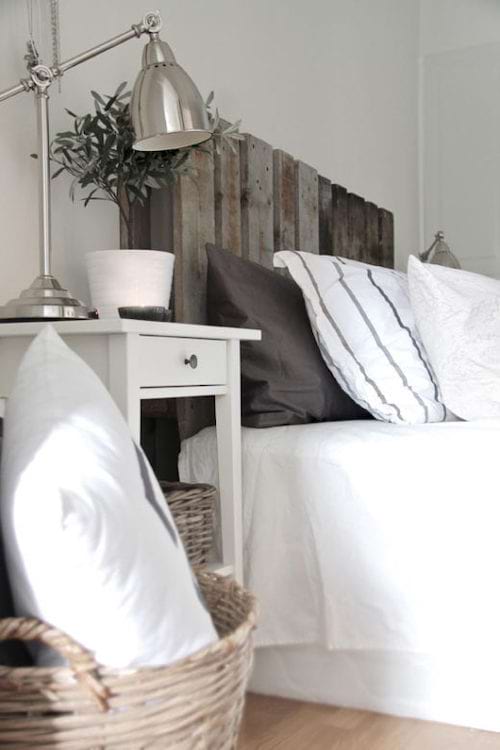 Un lit blanc avec une palette en bois en tête de lit