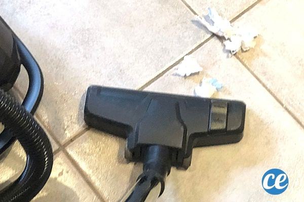 Un aspirateur qui aspire du papier blanc au sol 