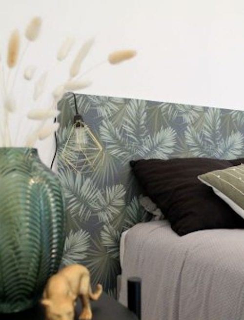 Une tête de lit en papier peint foncé avec des motifs de fleurs vertes