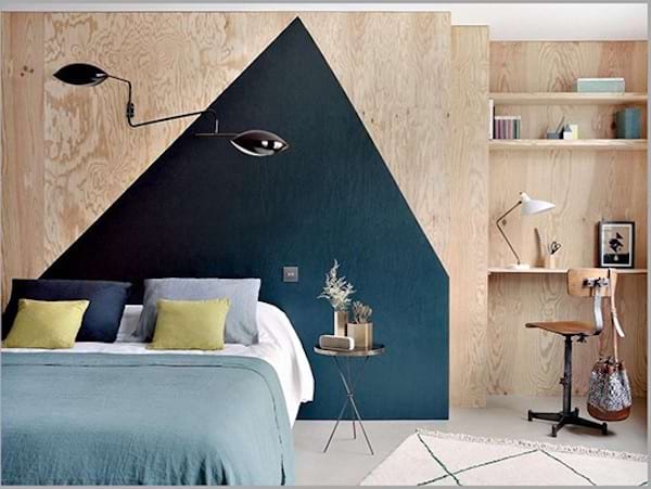 Une grande peinture géométrique bleue qui est faite au mur derrière un lit