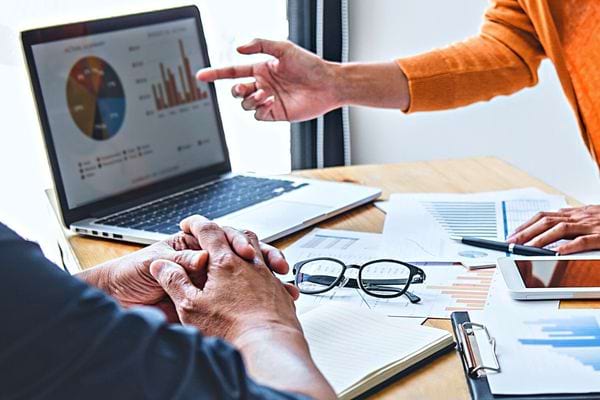 Des personnes sur un bureau avec plusieurs données et une paire de lunette