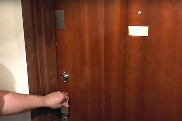 Une personne tenant la poignée d'une porte marron fermée