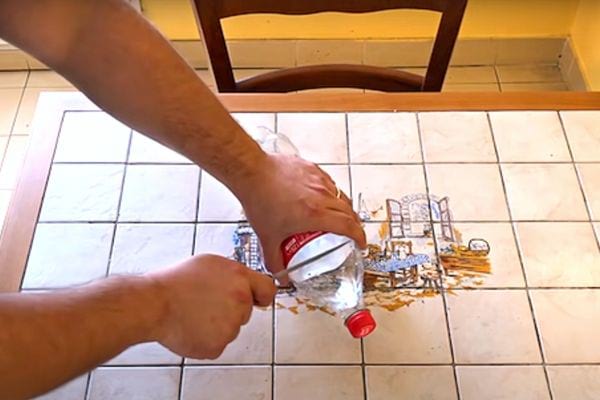 Une personne découpant une bouteille de coca à l'aide d'un couteau