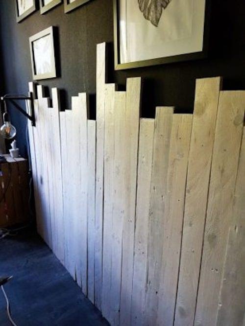 Une tête de lit en palettes de bois qui sont assemblées pour créer un cadre de lit