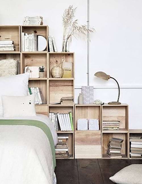 Une tête de lit faites de caisses en bois empilées les unes sur les autres et peintes en blanc
