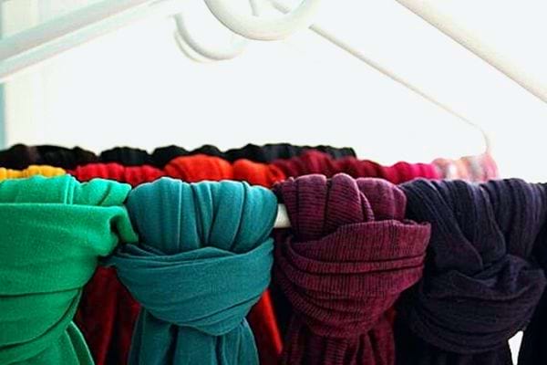 Plusieurs écharpes de multiples couleurs suspendues à des cintres 