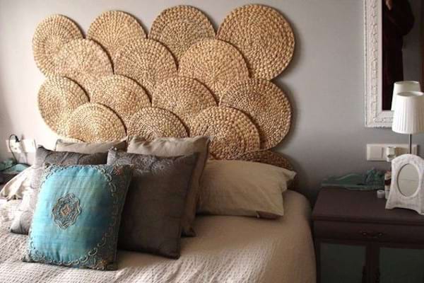 Plusieurs sets de tables accrochés au mur au dessus d'un lit avec plusieurs oreillers