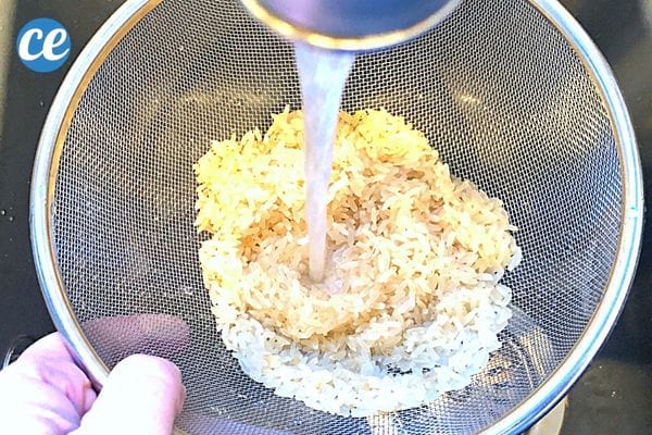 De l'eau qui rince du riz dans une passoire 
