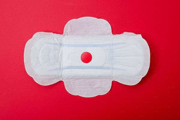 Une serviette hygiénique ouverte sur un fond rouge 