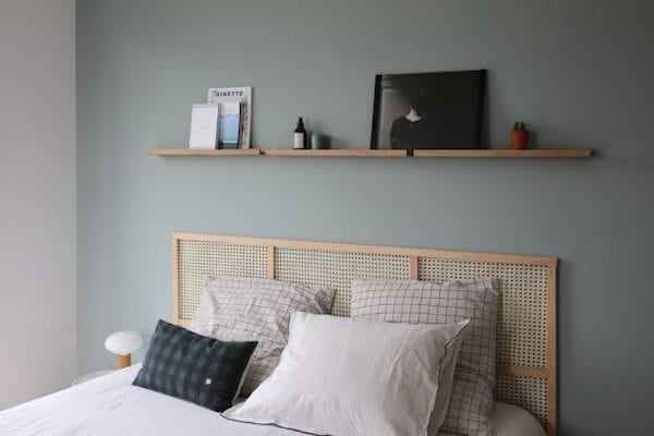 Une tête de lit qui est faite de cannage tissé fixée au mur derrière le lit faite de bois