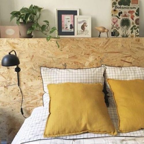 Un lit avec des oreillers jaunes et une tête de lit faites avec des matières naturelles