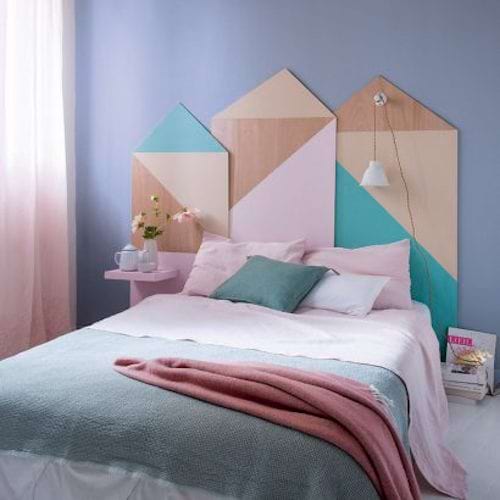Une tête de lit en bois et en couleurs en forme rectangulaire montée sur un mur derrière un lit