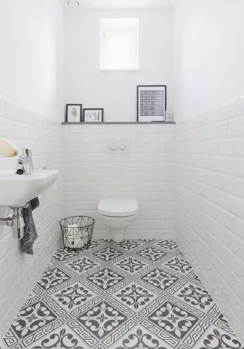 Toilets with white tiles on the wall and patterns on the floor 