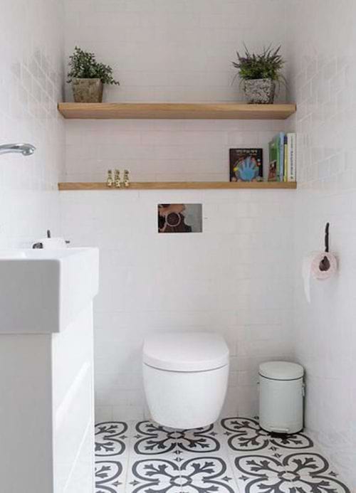 A toilet with two wooden shelves just below and patterns on the floor 