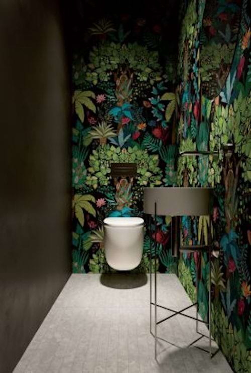 A toilet with a jungle-style wallpaper full of flowers 