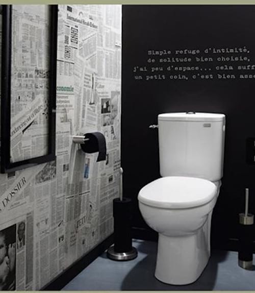 Lots of newspapers stuck to the wall in a toilet 