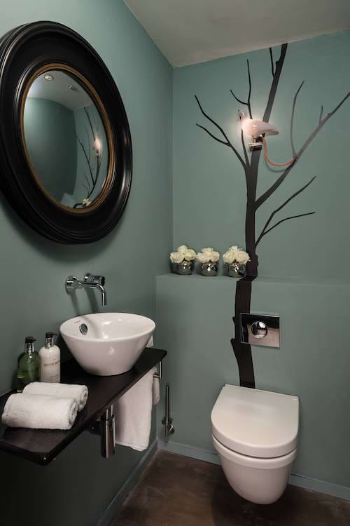 Des toilettes avec des murs bleus et un arbre peint en noir dessus
