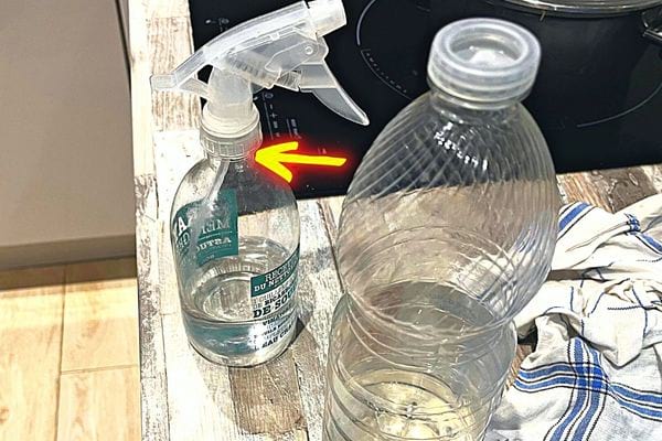 Une bouteille de vinaigre blanc avec un vaporisateur à côté 