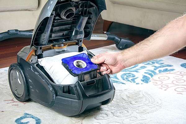 Une personne tenant le sachet d'un aspirateur 