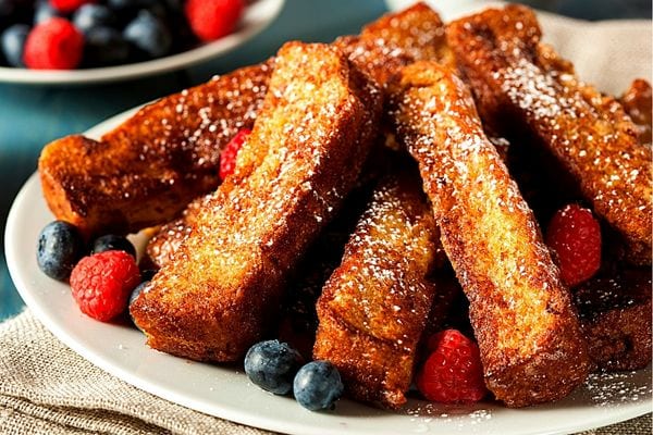 Une assiette blanche remplie de pain perdu avec des fruits rouges