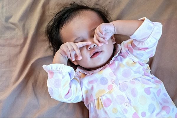 Un bébé couché qui se frotte les yeux 