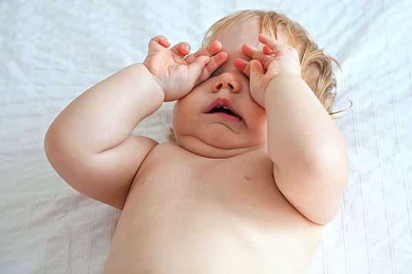 Un bébé qui frotte ses deux yeux 