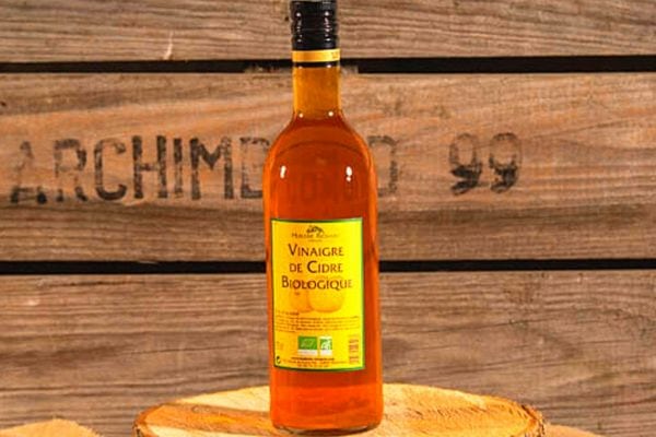 Une bouteille de vinaigre de cidre bio sur un tronc d'arbre