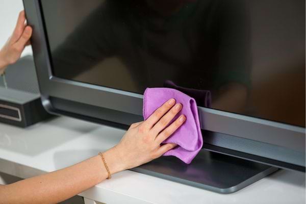 Une personne nettoyant sa télé noir avec un chiffon micro-fibres violet 