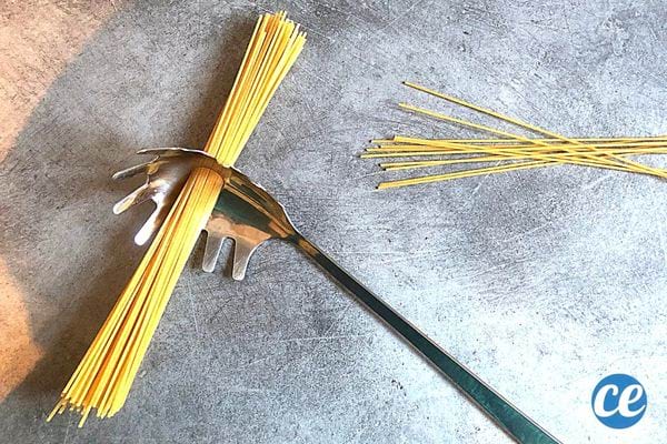Une cuillère à spaghettis avec plusieurs spaghettis dans le trou