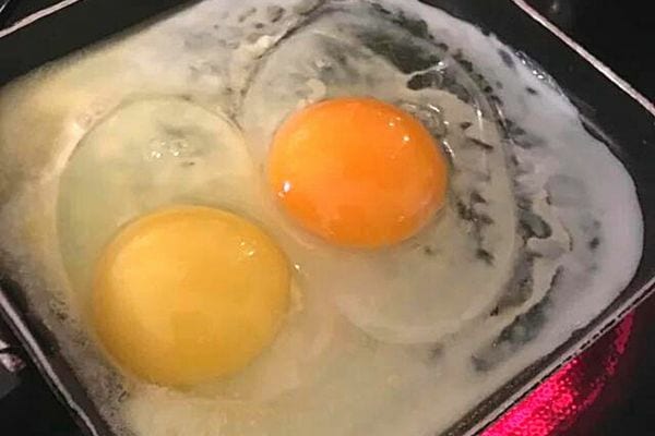 Deux jaunes d'oeufs qui sont en train de cuire dans une poêle