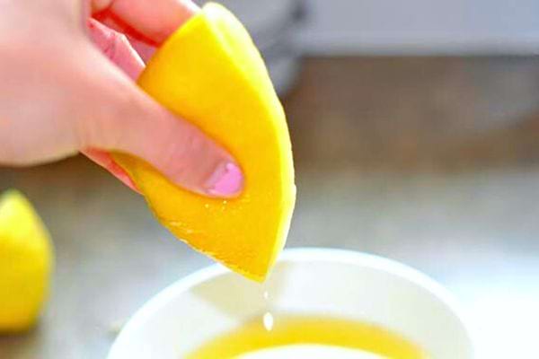Une femme qui presse un citron au dessus d'une tasse 