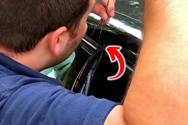 Un homme mettant un fil en fer dans l'espace d'une portière 