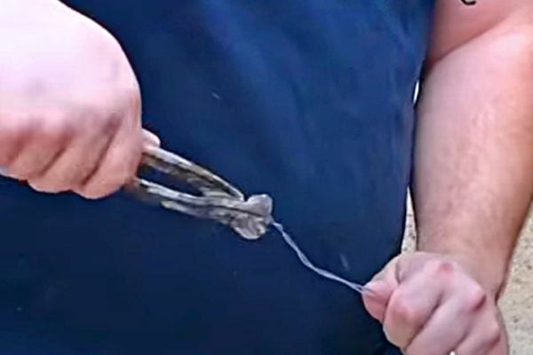 Un homme tenant une pince avec un fil en fer 