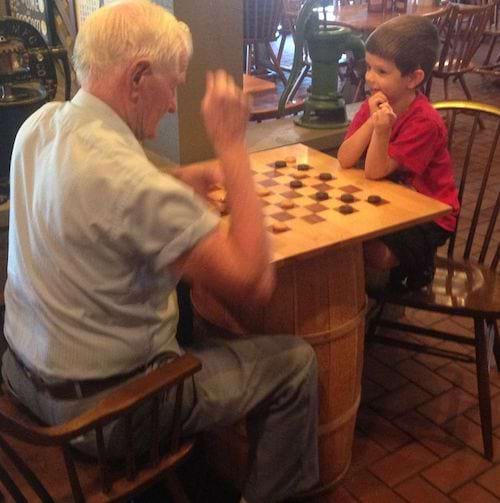 Un grand-père qui joue aux jeux des dames avec son petit-fils dans un restaurant