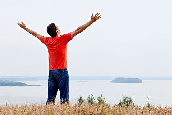 Un homme portant un tee-shirt rouge avec les deux bras ouvert en signe de bien-être 