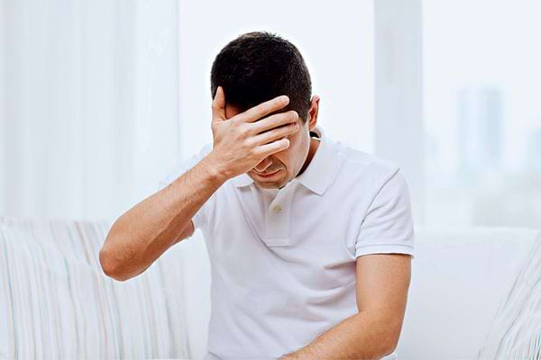 Un homme portant un tee-shirt blanc qui a l'air abattu 