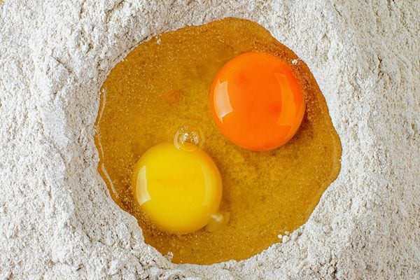 Deux jaunes d'oeuf avec l'un plus foncé que l'autre dans de la farine