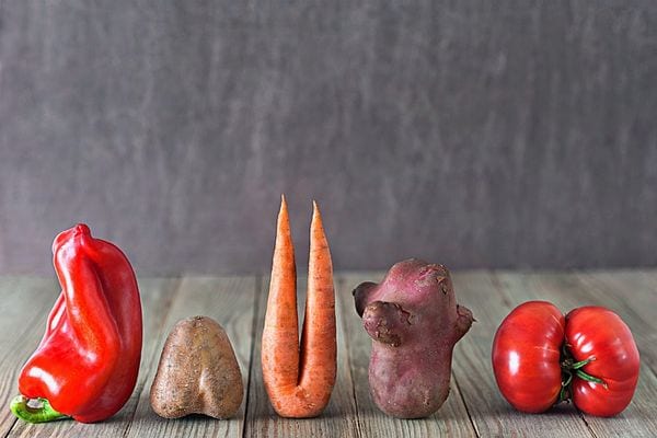 Plusieurs légumes qui sont côtes à côtes sur une table en bois 