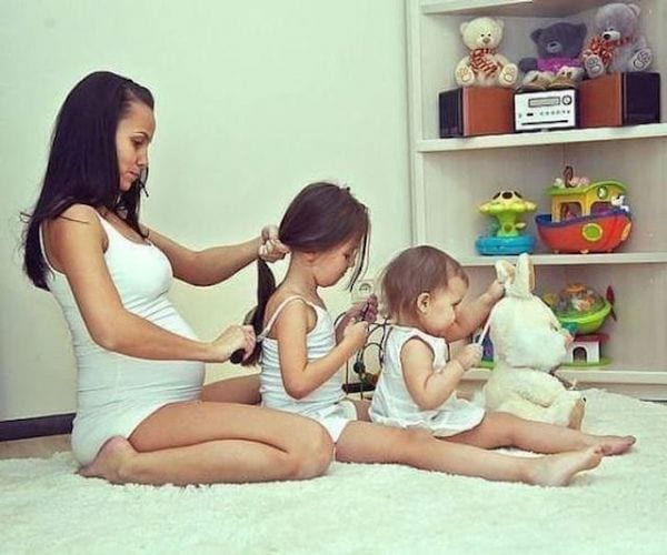 Une maman qui coiffe sa fille et sa fille qui coiffe sa petite soeur