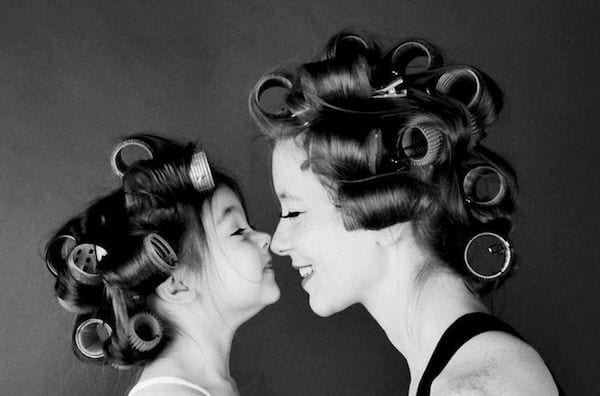 Une mère qui fait un bisous esquimau avec sa fille qui ont des bigoudis dans les cheveux