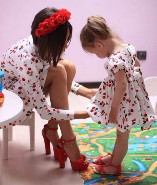 Une maman avec sa fille qui sont vêtu d'une robe blanche avec pleins de petites cerises