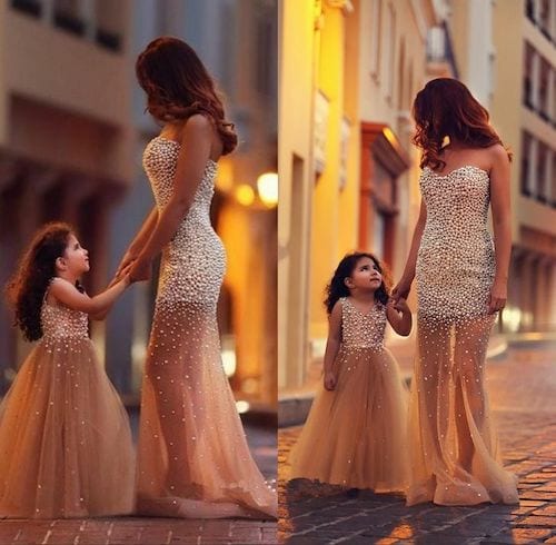 Une mère qui tient la main de sa fille avec une robe doré