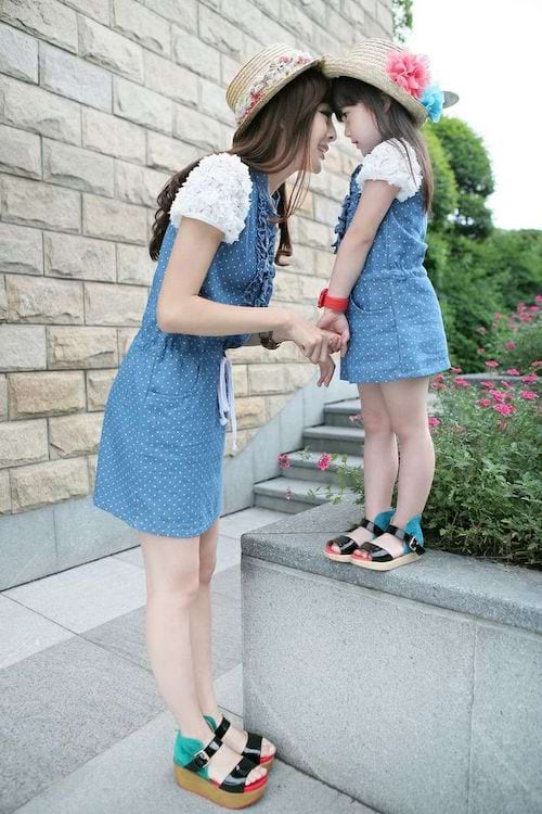 Une maman avec sa fille qui sont habillées en robe bleue avec des chapeaux de paille