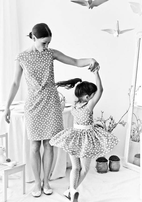 Une maman qui danse avec sa fille vêtu d'une robe avec pleins de petits point blancs