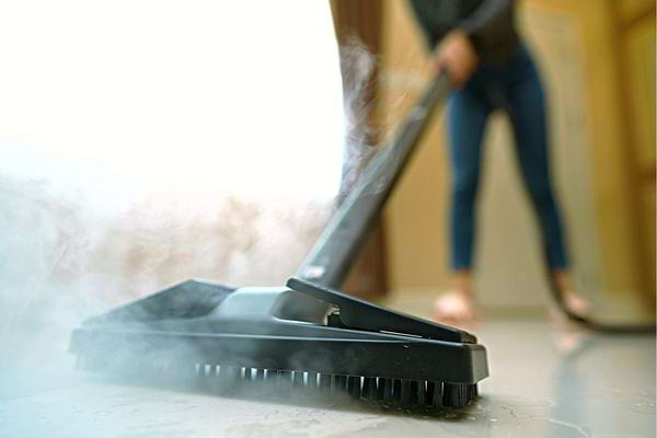 Une femme nettoyant son sol avec une machine à vapeur 