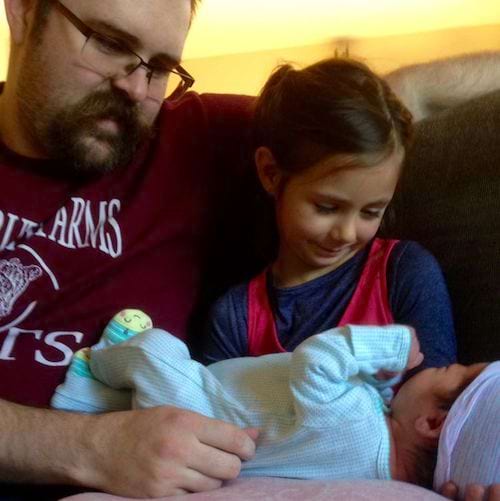 Un papa avec sa fille qui tient un bébé