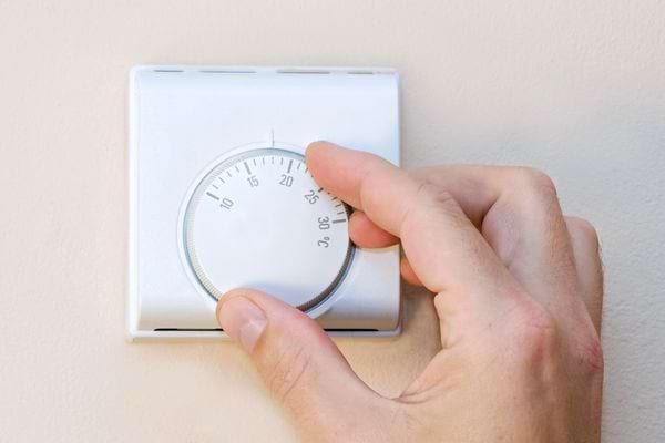 Une personne qui change la température d'un thermostat 