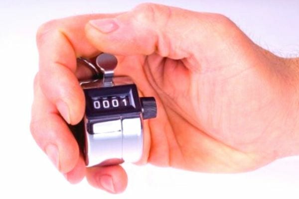 Une personne tenant un compteur dans sa main droite sur un fond blanc 
